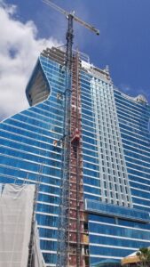 A building under construction with a huge Crane in front of it.